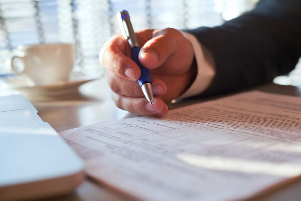 Hand holding pen completing a compliance document