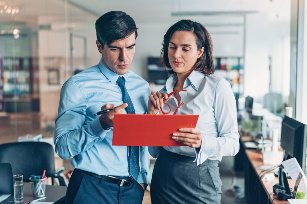 Man and women discussing cybersecurity concerns on red clipboard