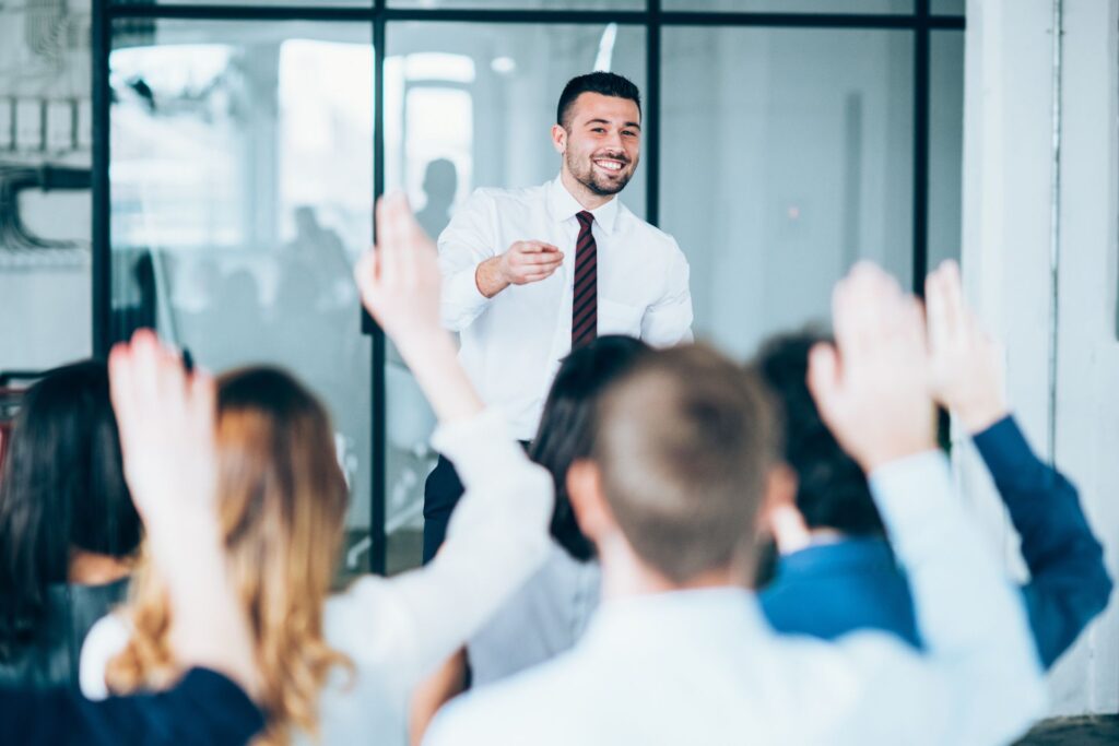 Man in front of a group of people asking questions and training employees