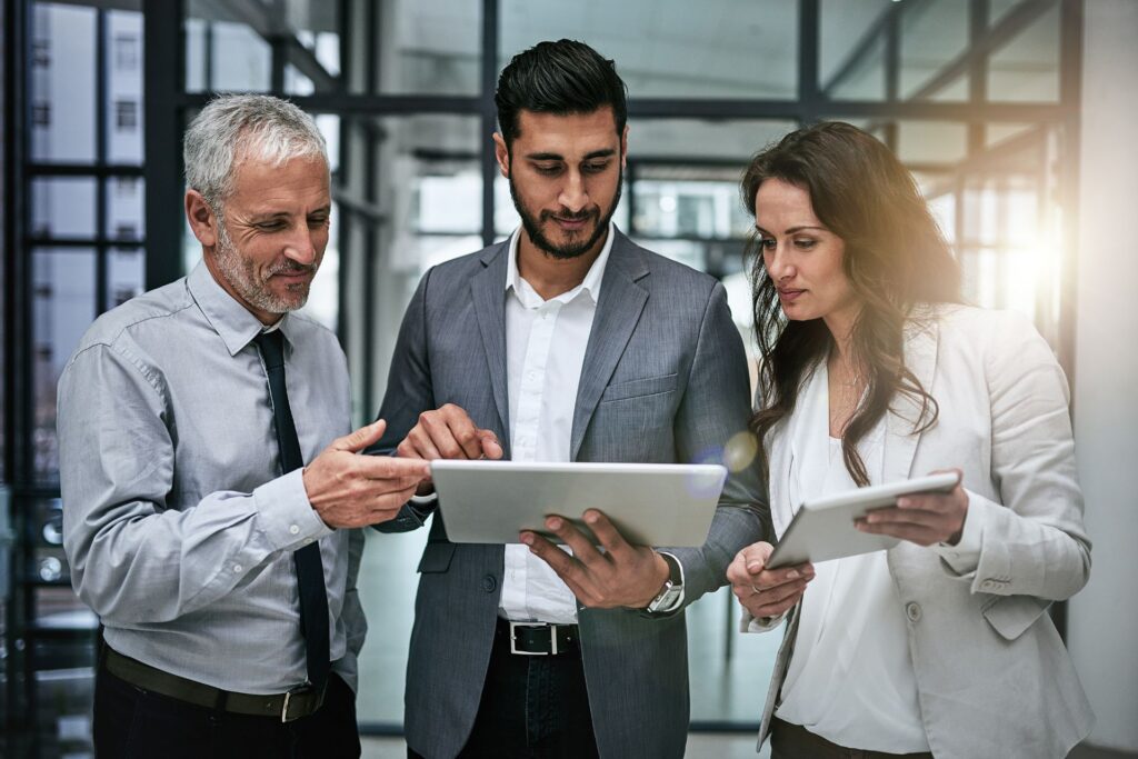 Two men and a women discussing client needs holding two tablets